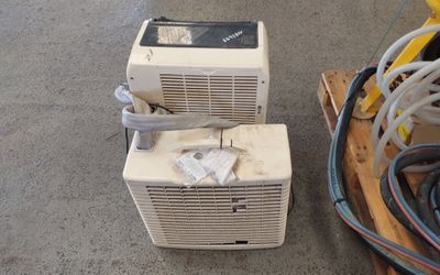two air conditioners sitting on a pallet next to a pile of wires