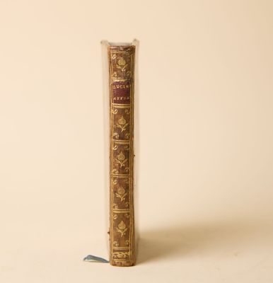 un vieux livre posé sur une table à côté d'un mur blanc