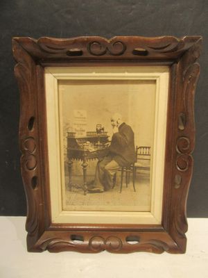une vieille photo d'un homme jouant du piano, dans un cadre en bois