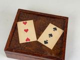 two playing cards in a wooden box on a white surface