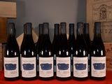 six bottles of red wine are lined up on a table