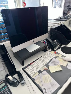 un bureau équipé d'un écran d'ordinateur, d'un clavier, d'un téléphone et d'autres fournitures de bureau