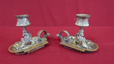 pair of antique silver candlesticks on a red background