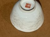 a white bowl with a red label sitting on a brown surface