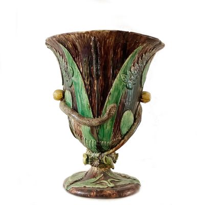 un vase vert et marron posé sur une surface blanche