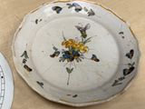 a plate with a flower design on it next to a plate with a clock on it