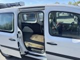 a small white van with its door open in a parking lot