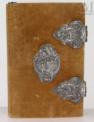 un vieux livre orné de décorations métalliques argentées, posé sur une table