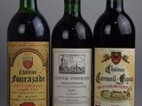 three bottles of red wine are lined up on a gray surface
