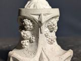 une petite statue représentant une femme avec des grappes de raisin sur la tête
