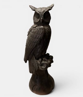 an owl statue sitting on top of a wooden stump