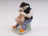 a figurine of a man sitting on a rock with a basket