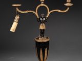 a black and gold table lamp with three candles on it