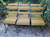 trois bancs en bois placés les uns à côté des autres dans l'herbe