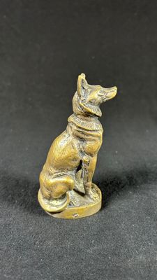 a small bronze statue of a dog sitting on top of a table