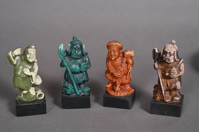 four different colored figurines of different shapes and sizes on black bases