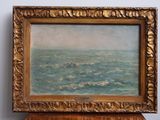 une peinture à l'huile représentant un bateau en mer, posée sur une table en bois