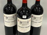 three bottles of red wine are lined up on a white surface