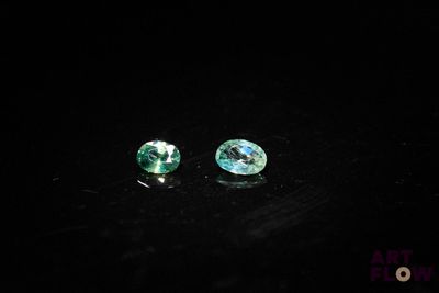 pair of green tourmaline gems on a black surface