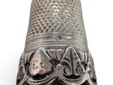 an antique silver thimble on a white background