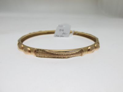 gros plan d'un bracelet en or sur une surface blanche