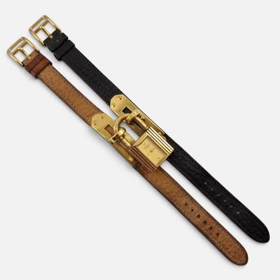 a close up of two belts with gold buckles on a white background