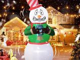 un bonhomme de neige gonflable muni d'un appareil photo, devant une maison