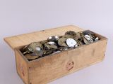 une boîte en bois remplie de pièces de monnaie posée sur une surface blanche