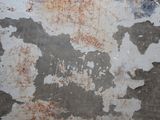peeling paint on the wall of a bathroom with a toilet in the corner