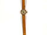 une vieille montre-bracelet avec un bracelet en cuir marron et un cadran blanc