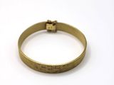 a close up of a gold bracelet on a white surface