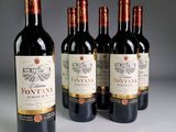 quatre bouteilles de vin rouge sont alignées sur une table
