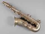 an old silver saxophone sitting on top of a gray surface
