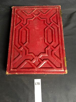 an old red book with a gold border and a black background