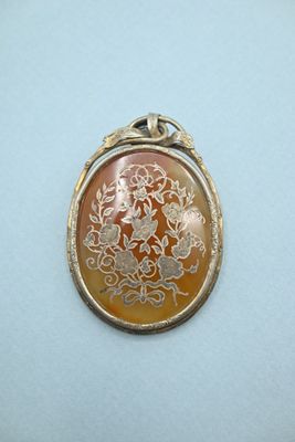 an image of a picture of a pendant with a flower design on it