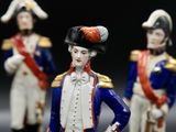 three figurines of men dressed in military uniforms