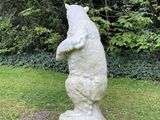 a statue of a bear on a pedestal in the grass