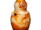 un vase orange orné de fleurs, posé sur une surface blanche