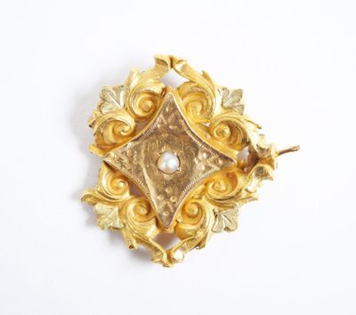 an image of a gold brooch with a pearl in the center
