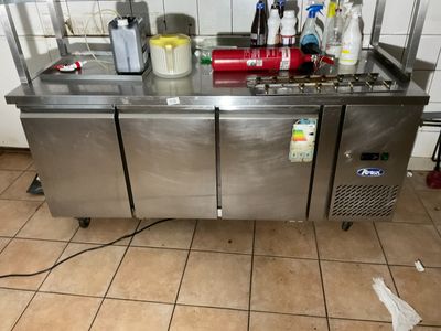 un plan de travail en inox sur lequel sont posés tout un tas de produits d'entretien