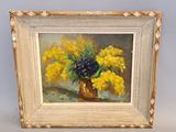 tableau représentant des fleurs jaunes et bleues dans un vase doré posé sur une table