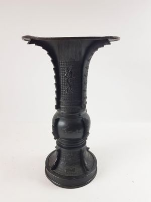 un vase noir posé sur une surface blanche