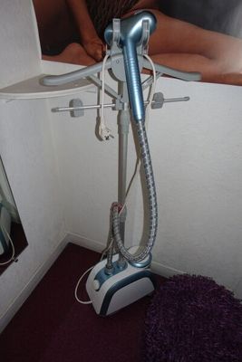 a woman sitting on a bed with a vacuum in her hand