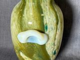 un vase vert avec une anse blanche sur fond gris