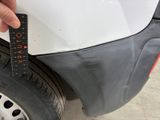 a person measuring the width of a car ' s bumper