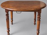 an oval dining table with turned legs and a wooden top