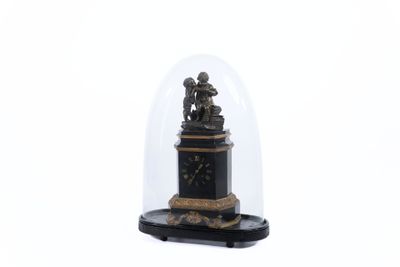 une petite horloge sous un dôme en verre, posée sur une surface blanche