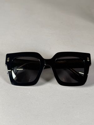 une paire de lunettes de soleil noires posée sur une table blanche