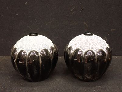 deux vases noirs et blancs posés sur une surface noire