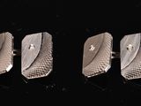 three silver cufflinks on a black surface with a black background